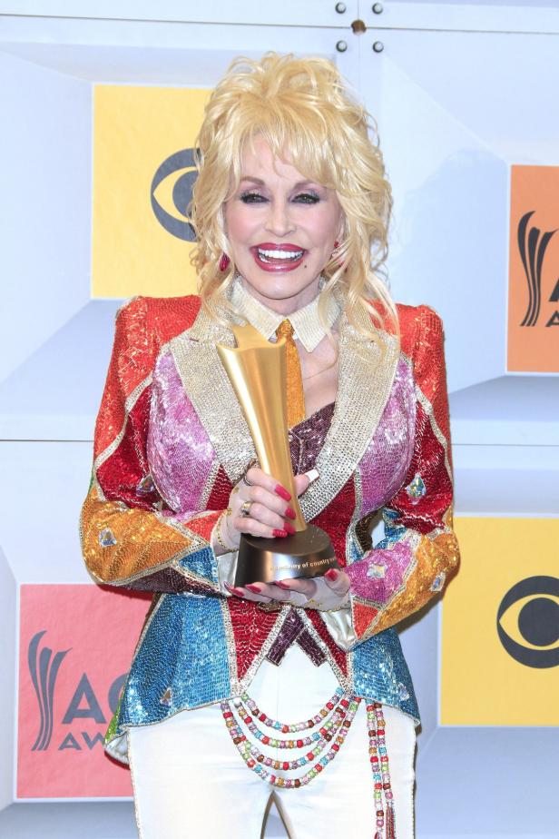Dolly Parton hält eine Trophäe der Academy of Country Music in den Händen.