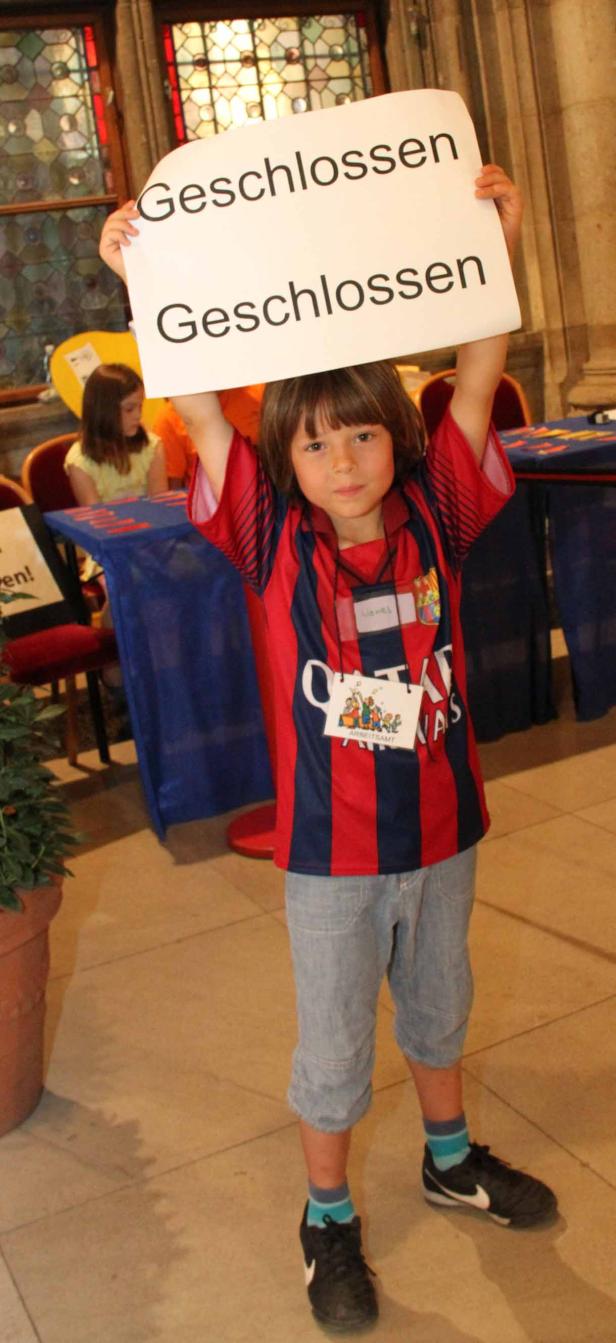 Ein Junge hält ein Schild mit der Aufschrift „Geschlossen“ hoch.