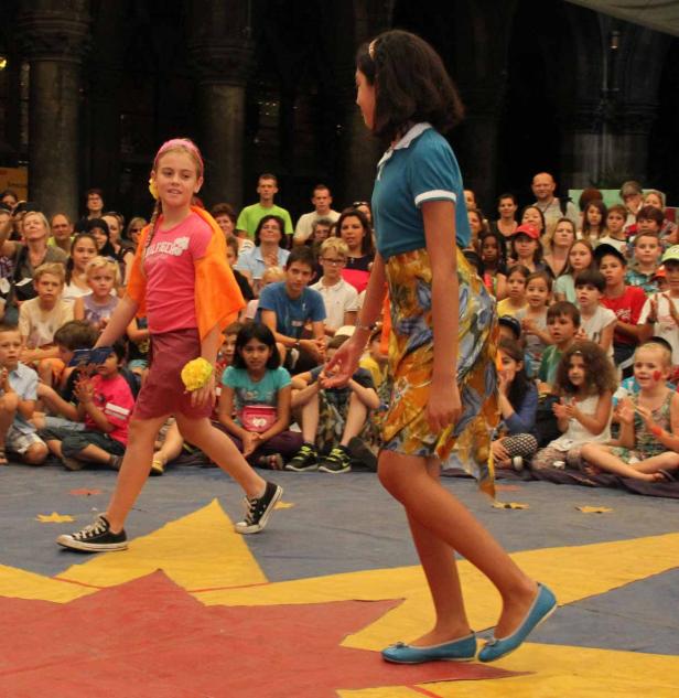 Zwei Mädchen präsentieren Mode vor einem Publikum.