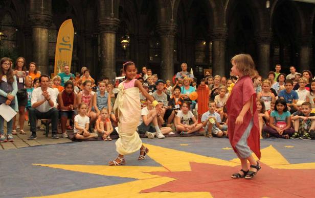 Zwei Mädchen führen vor einem Publikum ein Theaterstück auf.