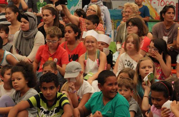 Eine Gruppe von Kindern und Erwachsenen sitzt zusammen und schaut in die Ferne.