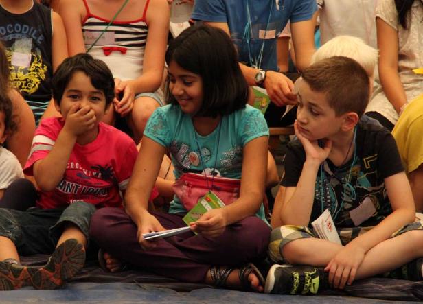 Eine Gruppe von Kindern sitzt auf dem Boden und beschäftigt sich mit verschiedenen Dingen.