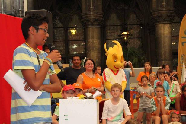 Ein Junge spricht bei einer Veranstaltung vor Publikum in ein Mikrofon.