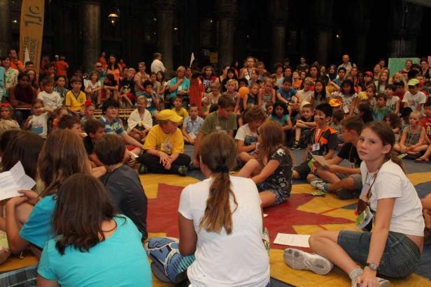 Eine große Gruppe von Kindern sitzt auf dem Boden in einem Raum.