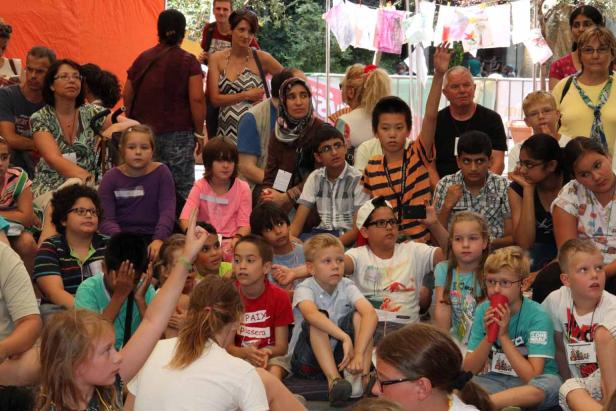 Eine Gruppe von Kindern und Erwachsenen sitzt zusammen im Freien.