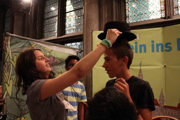 Ein Mädchen setzt einem Jungen einen schwarzen Hut auf den Kopf.