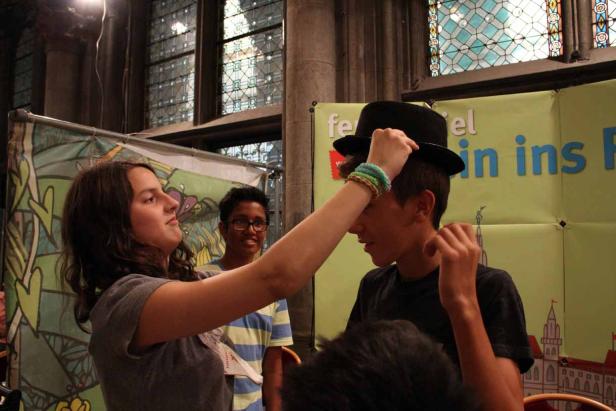 Ein Mädchen setzt einem Jungen einen schwarzen Hut auf.