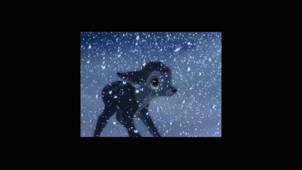 Ein junges Reh steht im Schneefall.
