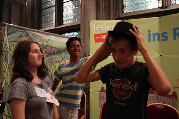 Drei Jugendliche posieren vor einem Stand mit der Aufschrift „ferieX ins R“.