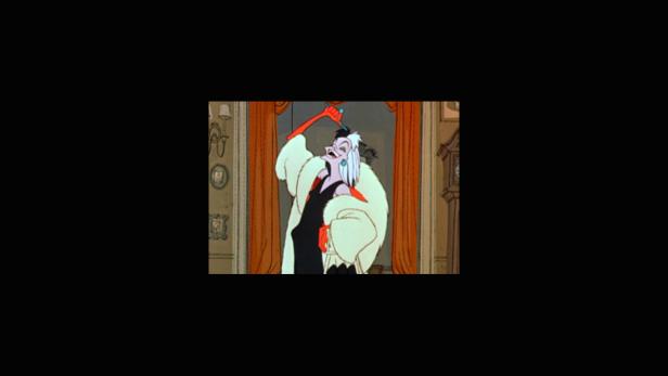 Cruella de Vil mit weißem Pelzmantel und Zigarettenspitze in der Hand.