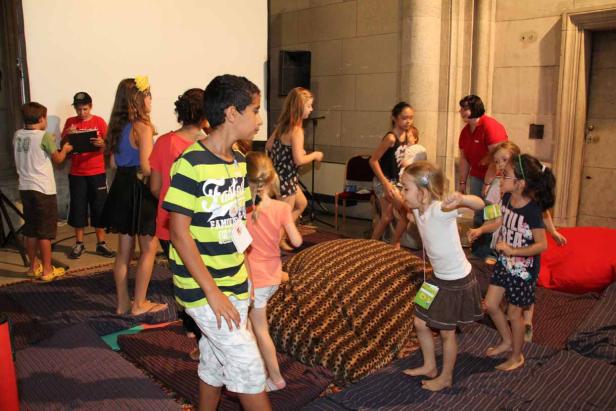 Eine Gruppe Kinder spielt barfuß in einem Raum mit Kissen und Matten.