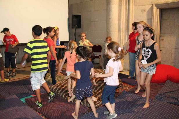 Eine Gruppe Kinder spielt barfuß in einem Raum mit Kissen und Matten.