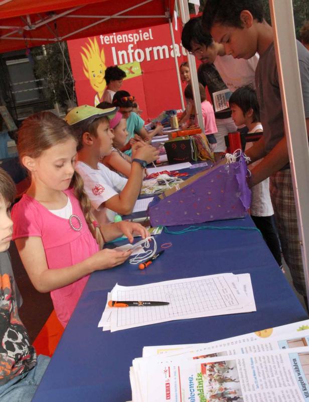 Kinder nehmen an einem Ferienspiel-Informationsstand teil.
