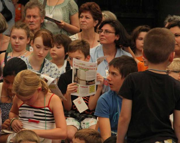 Eine Gruppe von Kindern und Erwachsenen liest Zeitungen und Broschüren.