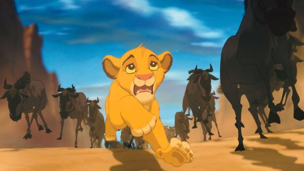Simba rennt in einer Szene aus „Der König der Löwen“ vor einer Gnu-Herde davon.