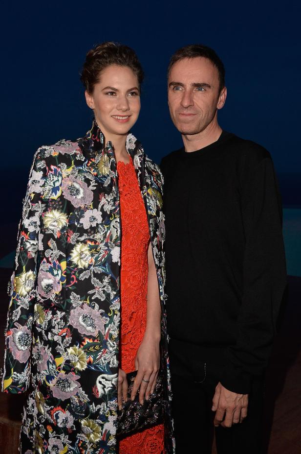 Eine Frau in einem floralen Mantel und ein Mann in Schwarz posieren nebeneinander.