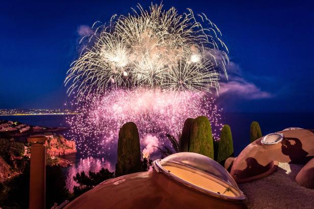 Ein Feuerwerk erhellt den Nachthimmel über einer Küstenstadt.