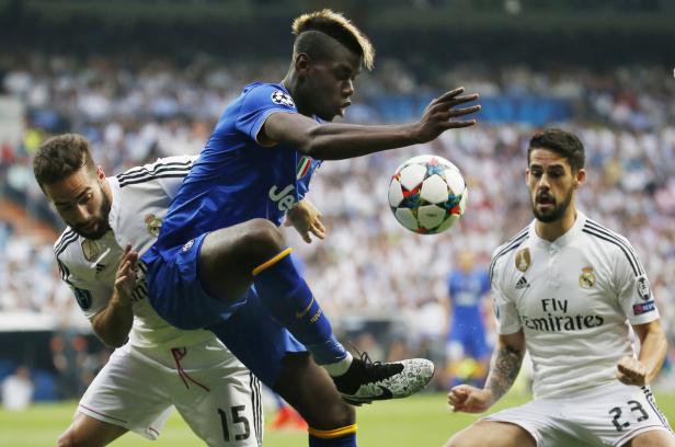 Ein Fußballspieler von Juventus Turin spielt den Ball, während zwei Spieler von Real Madrid zusehen.