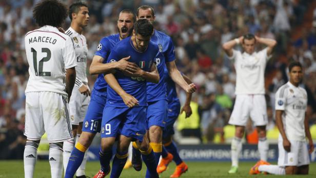 Fußballspieler von Juventus Turin feiern ein Tor, während Spieler von Real Madrid enttäuscht sind.