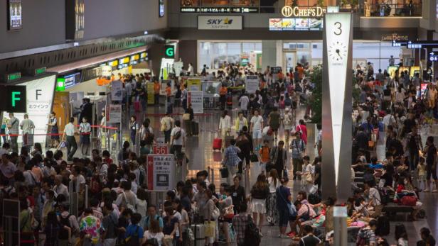 Viele Menschen drängen sich in einem belebten Flughafen-Terminal.