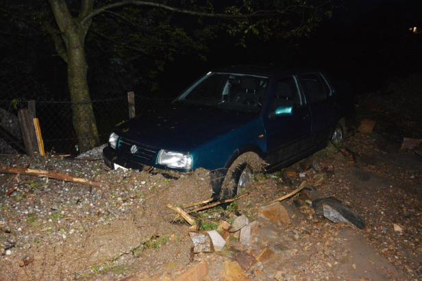 Ein blaugrünes Auto steckt im Schlamm fest.