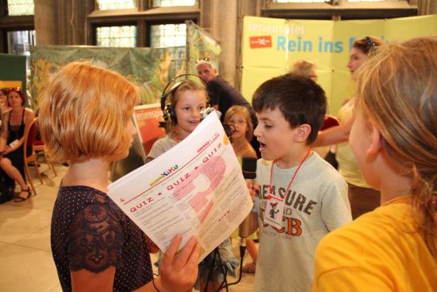 Kinder nehmen an einem Quiz mit Mikrofonen und Fragebögen teil.