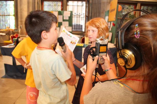 Kinder führen ein Interview mit Mikrofon und Aufnahmegerät durch.