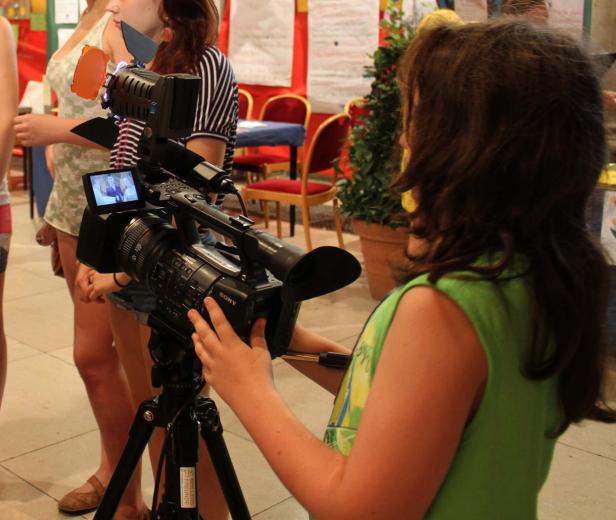 Ein junges Mädchen bedient eine professionelle Videokamera auf einem Stativ.