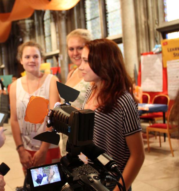 Drei junge Frauen werden mit einer Videokamera gefilmt.