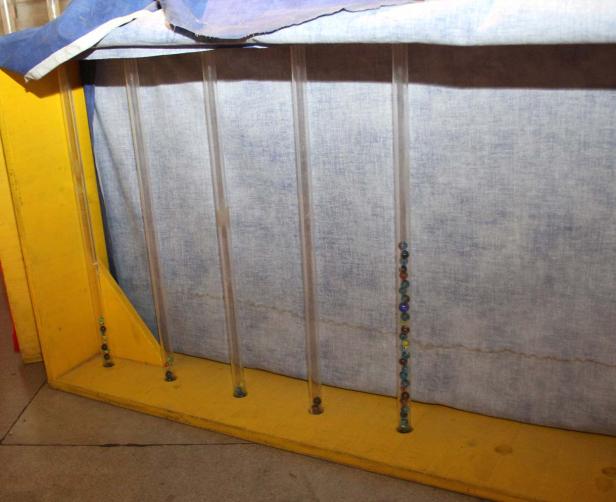 Murmeln befinden sich in Röhren, die in einem gelben Rahmen stehen.