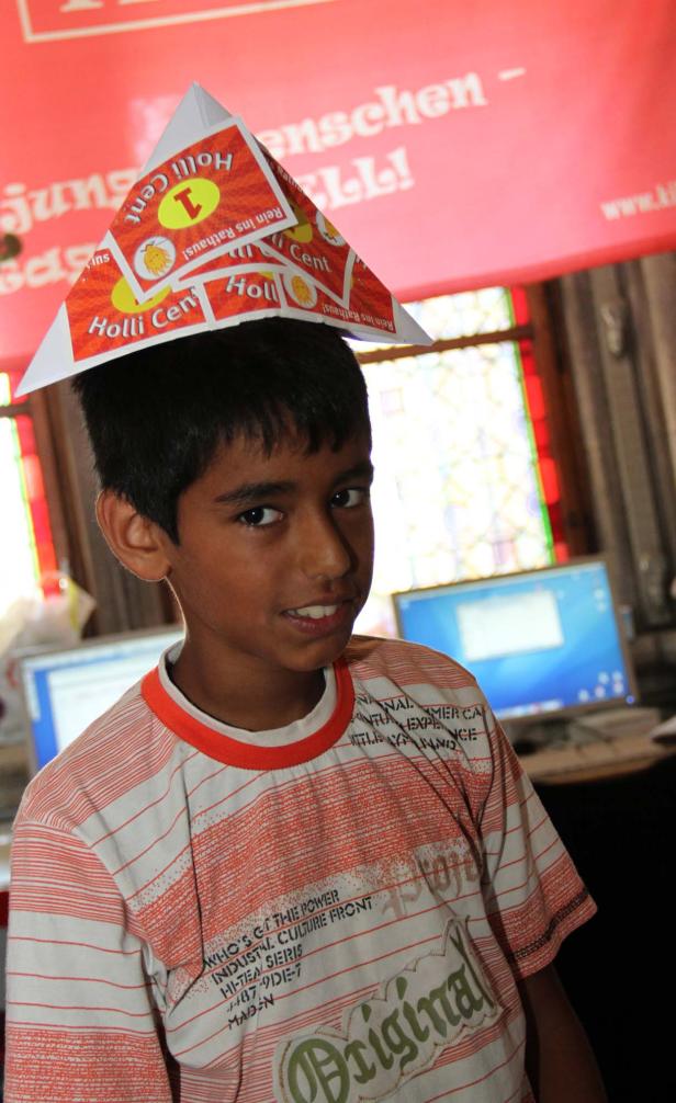 Ein Junge trägt einen Papierhut mit der Aufschrift „Holli Cent“.