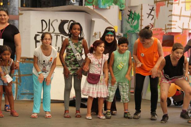 Eine Gruppe von Kindern und Betreuern posiert vor einer bemalten Wand.