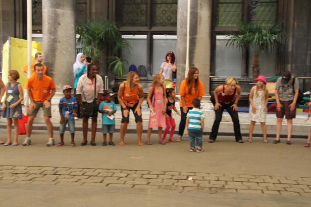 Eine Gruppe von Erwachsenen und Kindern macht Kniebeugen im Freien.