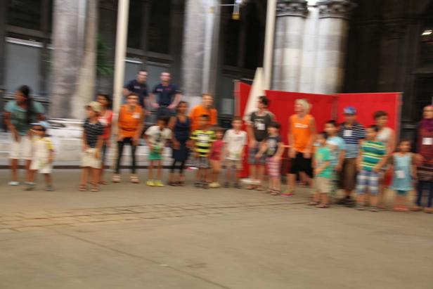 Eine Gruppe von Kindern und Erwachsenen steht vor einem Gebäude.