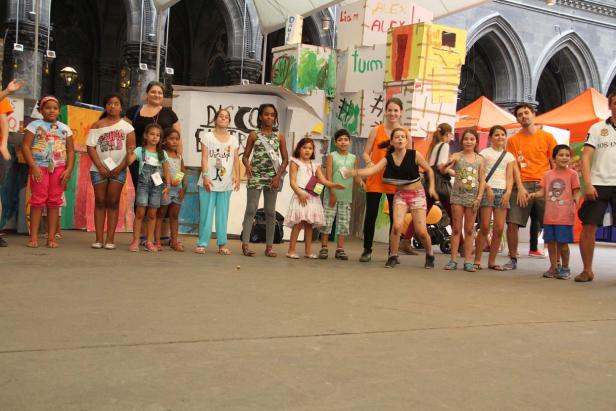 Eine Gruppe Kinder und Betreuer posiert vor einer Bühne mit bemalten Kartons.