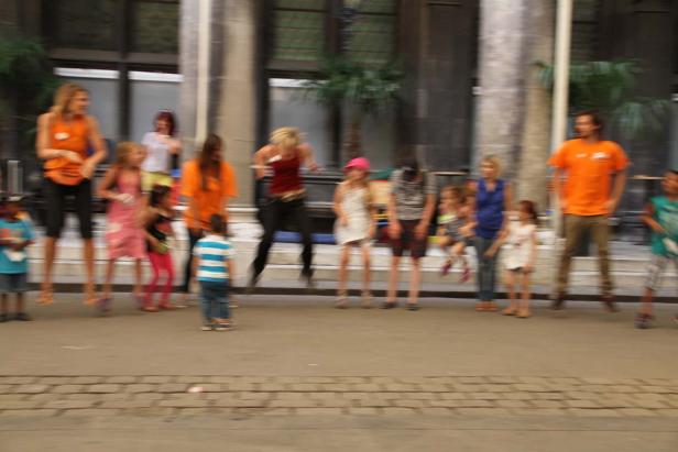 Eine Gruppe von Kindern und Erwachsenen steht vor einem Gebäude.