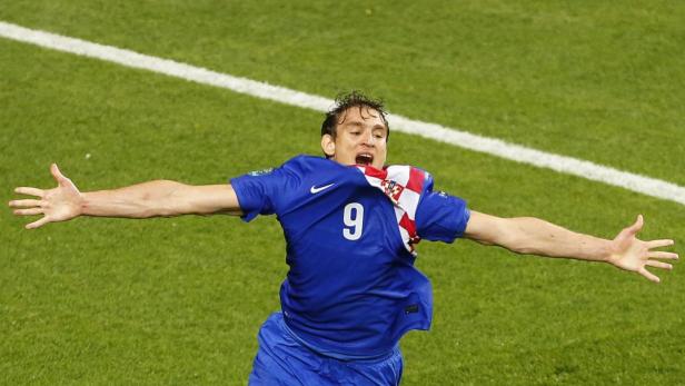 Ein kroatischer Fußballspieler jubelt mit ausgestreckten Armen auf dem Rasen.