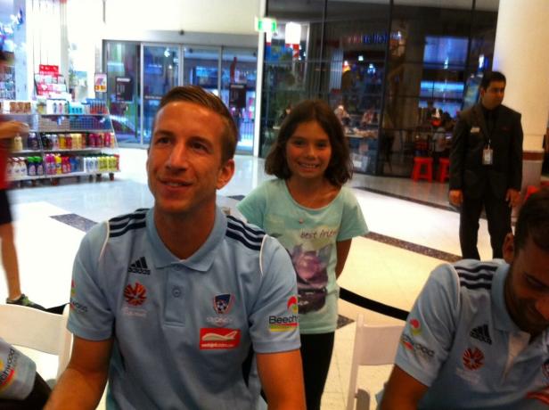 Ein Fußballspieler des Sydney FC gibt einem jungen Mädchen ein Autogramm.