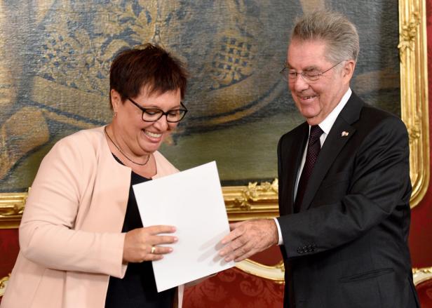 Eine Frau und ein Mann im Anzug betrachten lächelnd ein Blatt Papier.