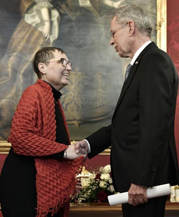 Eine Frau und ein Mann schütteln sich die Hände vor einem Gemälde.