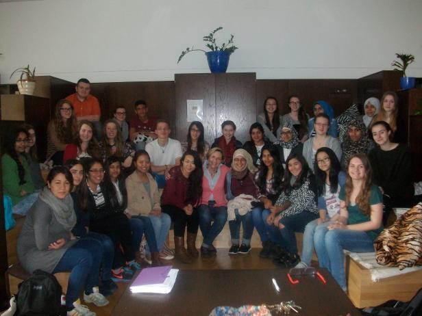 Eine Gruppe von etwa 30 jungen Menschen posiert für ein Gruppenfoto in einem Innenraum.