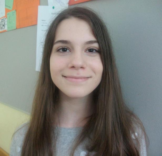 Porträt einer lächelnden jungen Frau mit langen, braunen Haaren.