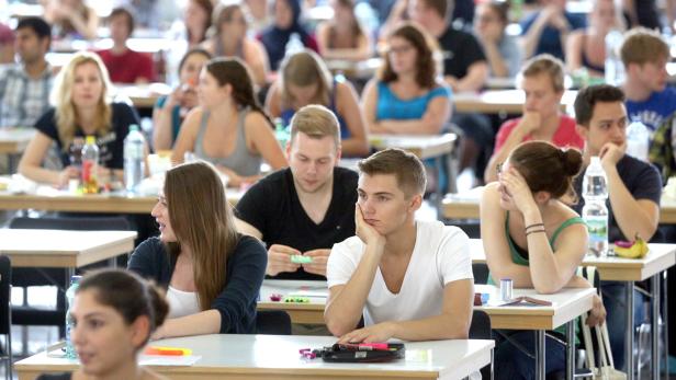Viele Studenten sitzen während einer Prüfung in einem großen Raum.