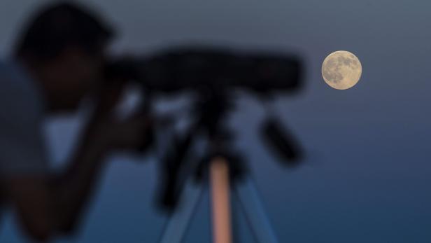 Eine Person beobachtet den Mond durch ein Teleskop.