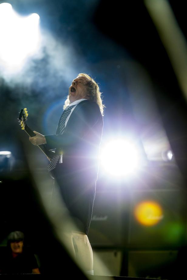 Angus Young von AC/DC spielt Gitarre und singt auf der Bühne.