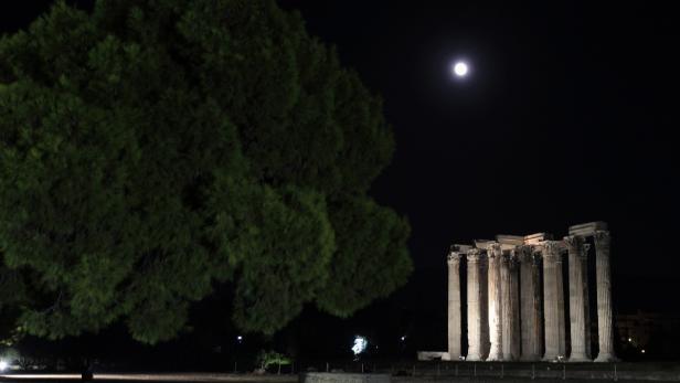 Der Tempel des Olympischen Zeus in Athen bei Nacht unter einem hellen Mond.