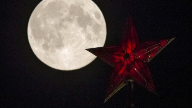 Ein roter Stern leuchtet vor dem Hintergrund eines hellen Vollmonds.