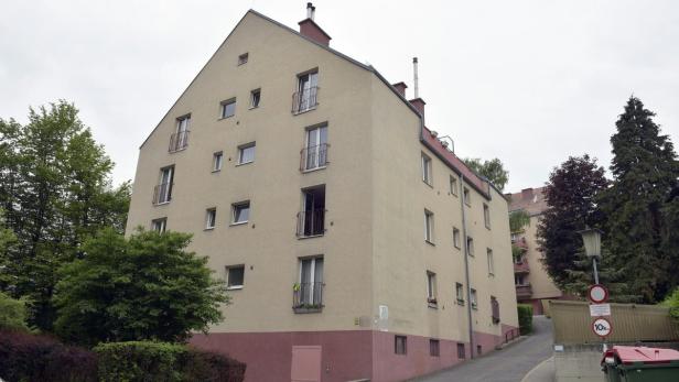 Ein Mehrfamilienhaus mit hellbeiger Fassade und kleinen Balkonen.
