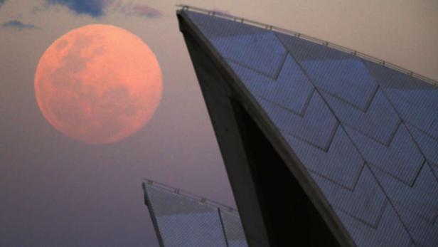 Der Vollmond geht über dem Opernhaus von Sydney auf.