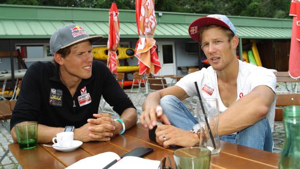 Erfolgreiches Doppel: Die Brüder Paul (li.) und Bernhard Sieber Zwei junge Männer mit Kappen sitzen an einem Tisch im Freien und unterhalten sich.